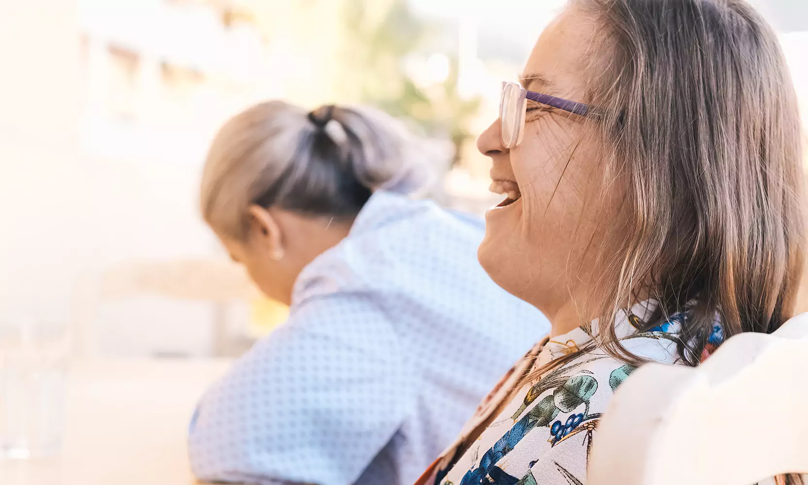 A woman with down syndrome laughing with her caregiver outdoors